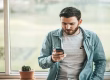 homem segurando celular para cancelar seguro residencial