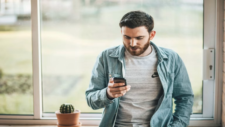 homem segurando celular para cancelar seguro residencial